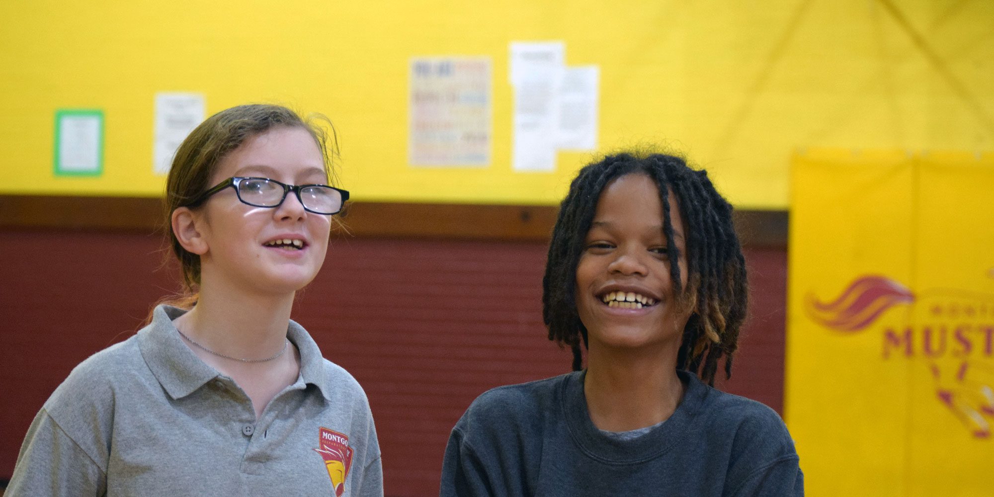 Two smiling students in the Montgomery Mustangs gym.